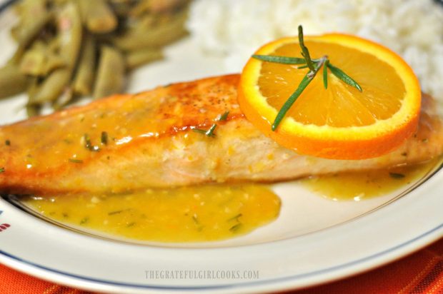 A orange rosemary glazed salmon fillet on plate, with green beans and rice.