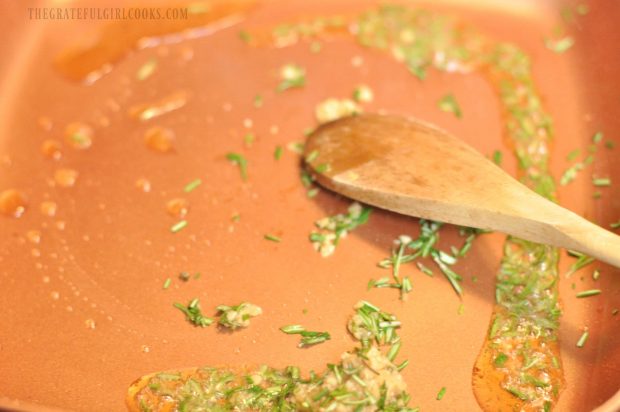 Minced garlic and rosemary cooking in copper skillet