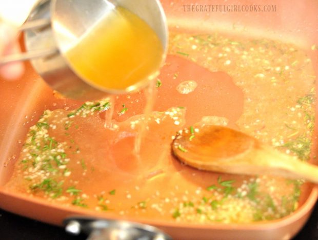 Chicken broth being poured into orange glaze sauce in skillet