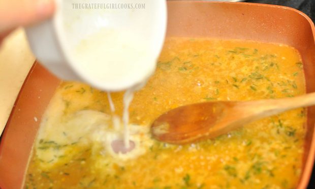 Cornstarch and broth being added to orange sauce in pan