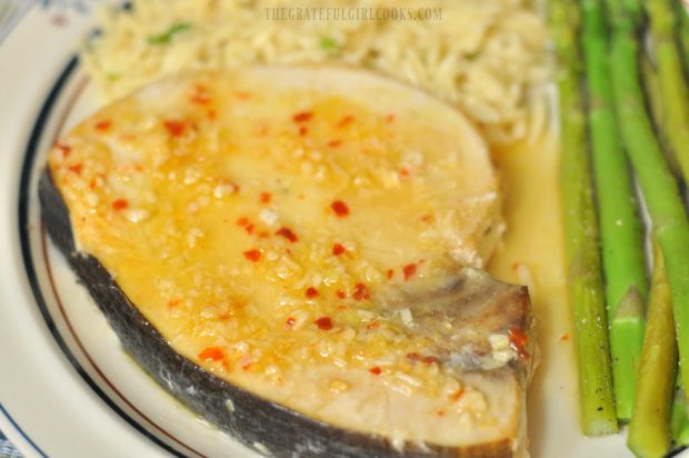 Swordfish with lemon garlic sauce, on plate with orzo and asparagus.