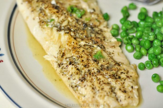 A piece of Trout In Lemon Garlic Butter Sauce on a plate, with peas.