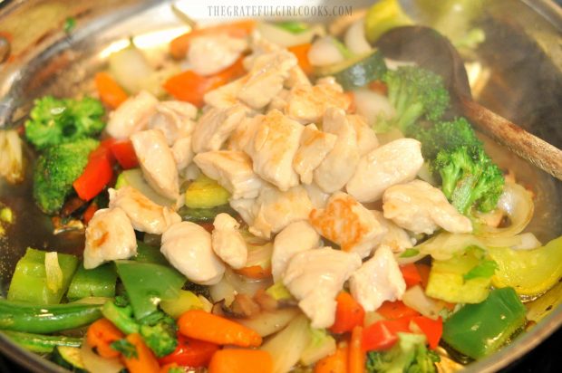 The cooked chicken is added to the vegetables in large skillet.