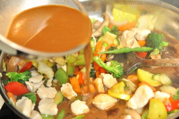 An Asian-inspired sauce is added to the skillet full of chicken veggie stir fry.