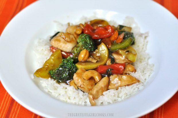 Chicken veggie stir fry is served on a bed of white rice.