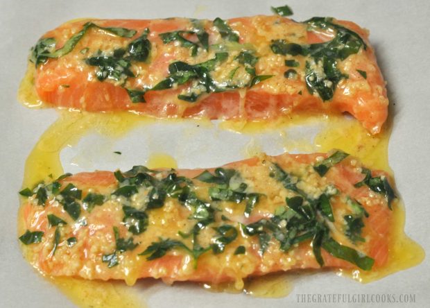 Salmon fillets are covered with the lemon butter herb sauce before baking.