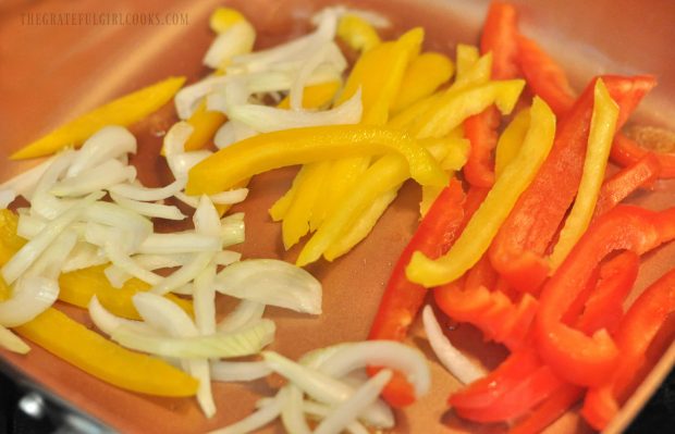 Yellow and red bell pepper slices with onions grilled in skillet