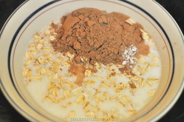 Milk is added to oats, and cocoa powder before mixing.
