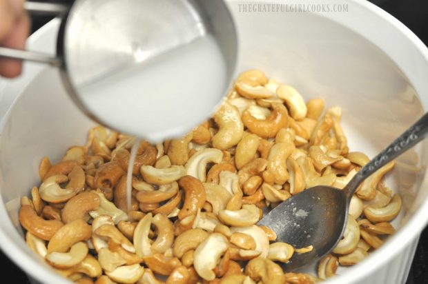 Coconut milk is added to cashews in bowl.