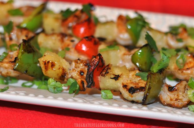 Close up of shrimp kabobs with pineapple, coconut and peppers on plate