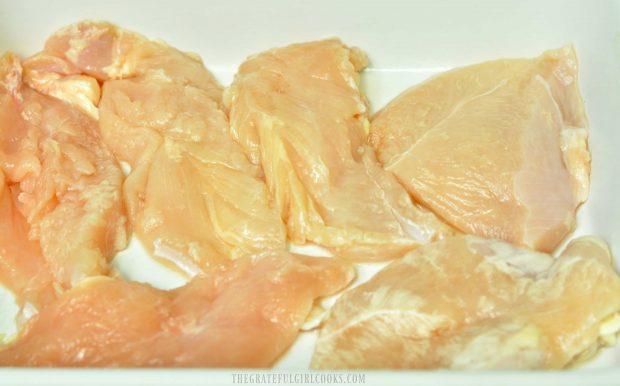 Chicken breasts are placed in a single layer in a baking dish.
