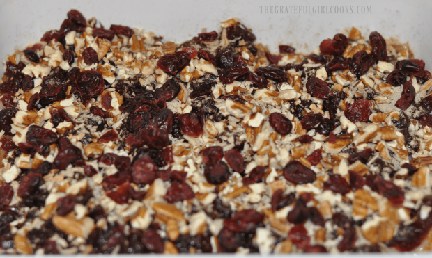 Dried cranberries are added to cranberry chicken in baking dish.