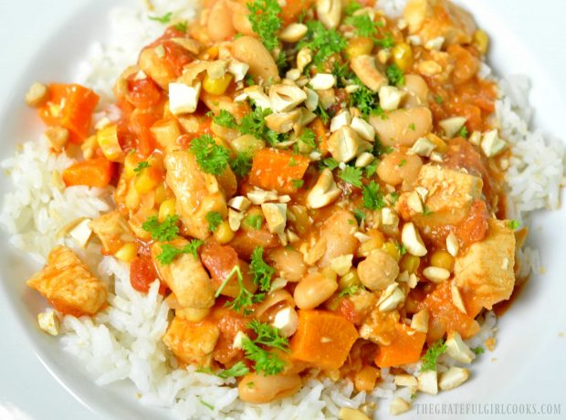 A white bowl containing rice, with chicken peanut stew on top.