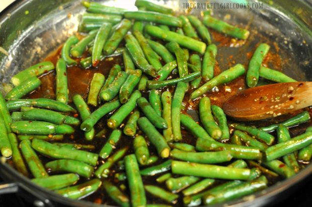 Spicy green beans finish cooking in the Asian sauce.