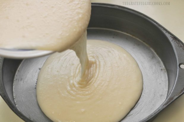 Cobbler batter is poured into a buttered cake pan.
