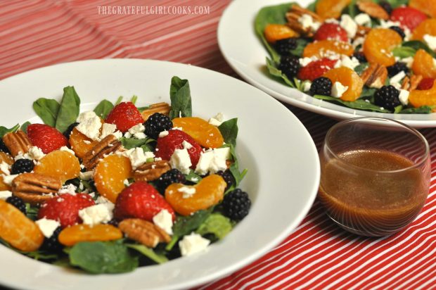 Two bowls of berry orange spinach salad, with citrus balsamic vinaigrette on the side.
