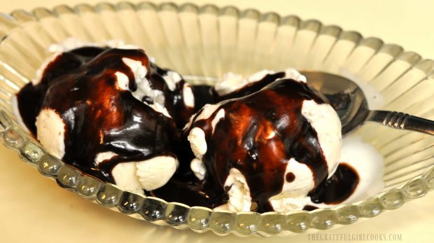 Homemade hot fudge sauce served over vanilla ice cream in dish.