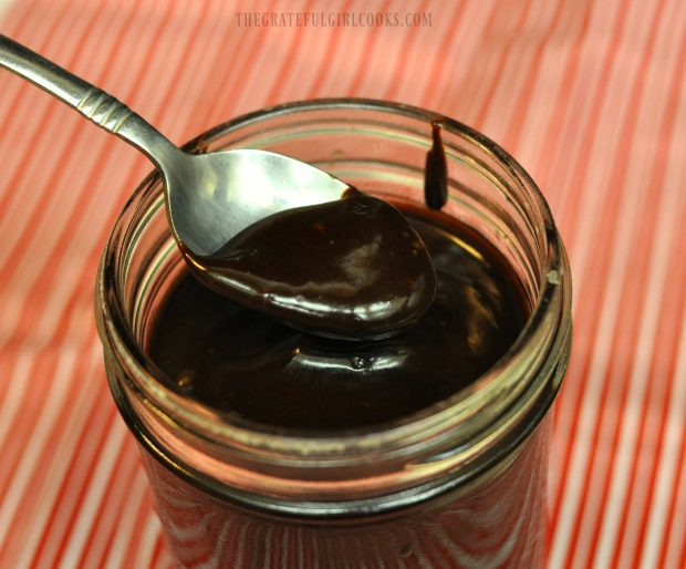 Spoonful of thick hot fudge sauce, over a glass jar