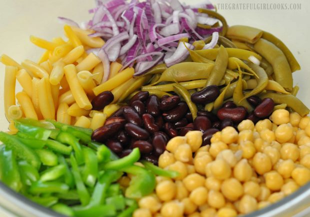 4 types of beans for salad, with green pepper and red onion in bowl.