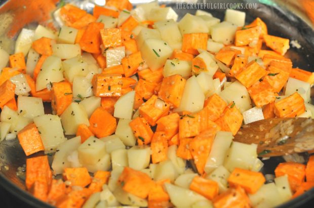 Potatoes, rosemary, onions and spices are cooked in skillet.