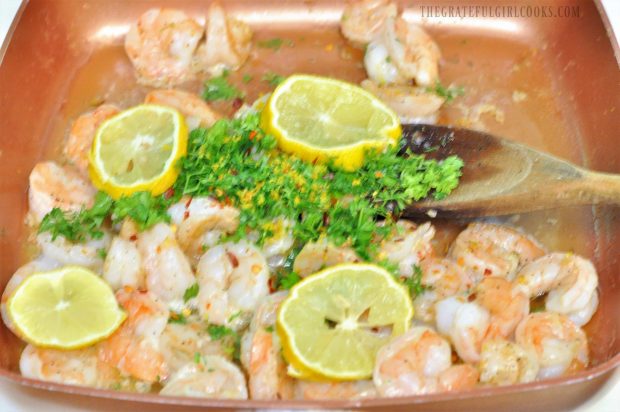 Cooking the shrimp scampi with lemons, lemon zest and parsley in a skillet.