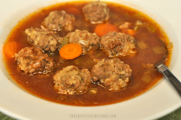 A bowl of albondigas soup, with meatballs and carrots.