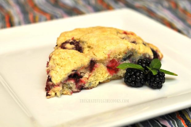 Blackberry scone on a white plate with a mint garnish.