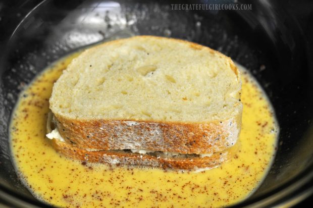 Stuffed French toast soaking up egg mixture before cooking