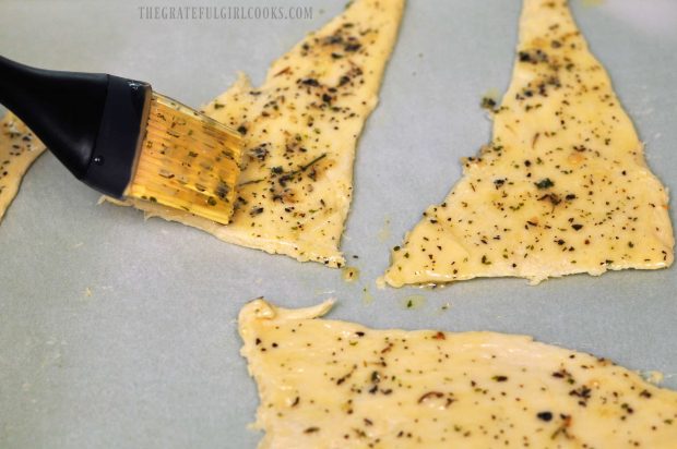 Crescent roll dough is unwrapped and brushed with seasonings.