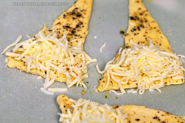 Shredded mozzarella cheese is added to cheesy garlic crescent rolls before baking.