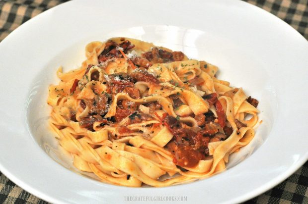 Fresh tomato, bacon onion fettucine is served in white bowl.