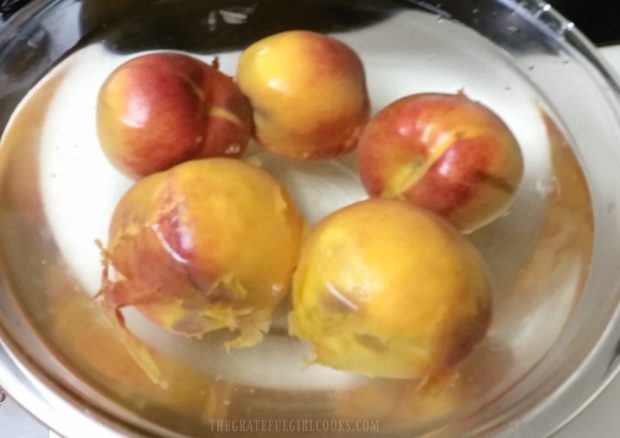 The quickly boiled peaches are placed into ice water.