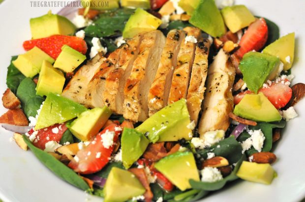 Avocado chunks added to spinach salad, along with dressing.