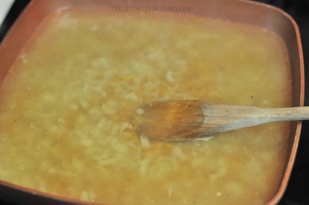 Chicken broth and wine are added to toasted orzo in pan.