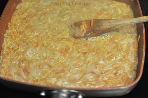 Toasted orzo begins to absorb chicken broth and wine in skillet as it cooks.