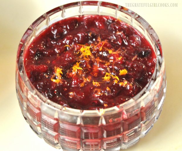 Whole Berry Cranberry Orange Sauce is served in glass bowl with orange zest garnish.