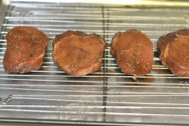 Marinated pork chops are placed on wire rack to broil.