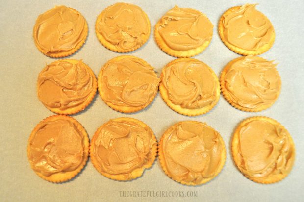 Creamy peanut butter is spread on Ritz cracker for cookies.