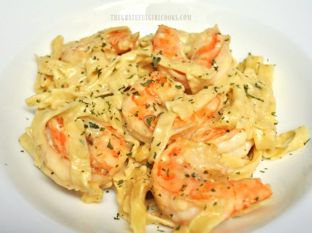 A serving of garlic parmesan pasta and shrimp, in a white bowl.
