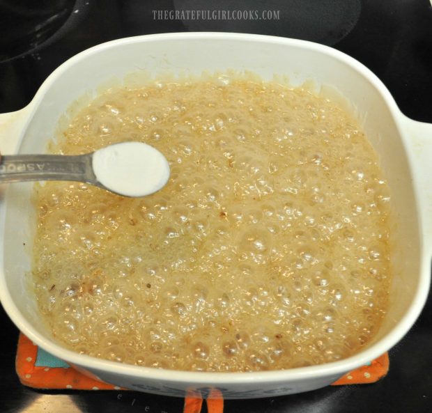 Baking soda is sprinkled over the top of the pecan brittle mixture.