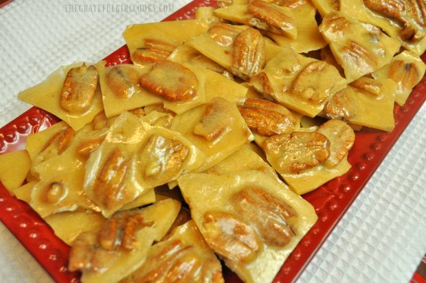 Microwave Pecan Brittle is broken into pieces and served, on red platter.