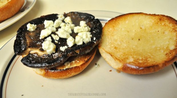 Cooked portobello mushroom and blue cheese crumbles are added to hamburger bun.