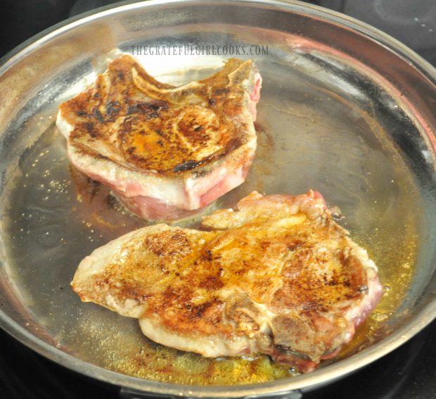 Pork chops are seared until brown on both sides before baking.