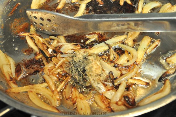 Thyme and garlic is added to cooked onions for smothered pork chops gravy.