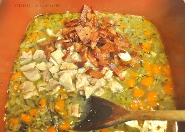 Chicken and bacon are added to the pot full of chicken wild rice soup.