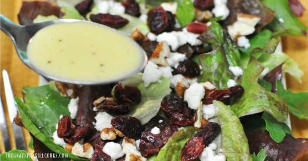 Pouring the creamy lemon salad dressing over a mixed green salad.