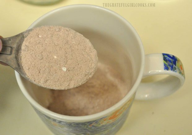 Measuring the mug cake mix into microwaveable mug.