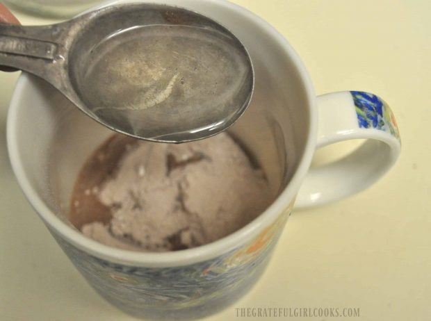 Water is added to the cake mix in mug.