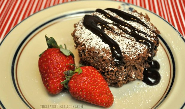 Chocolate mug cake, topped with powdered sugar and chocolate syrup.