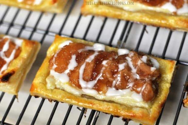 Close up photo of apple cream cheese pastries with glaze, on wire rack.